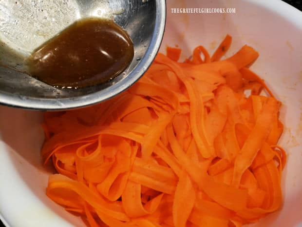 Homemade salad dressing is poured over the carrot ribbon salad.