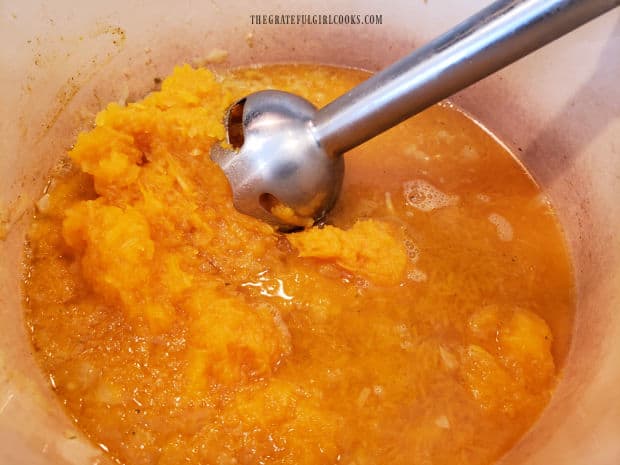 An immersion blender is used to puree the soup ingredients.