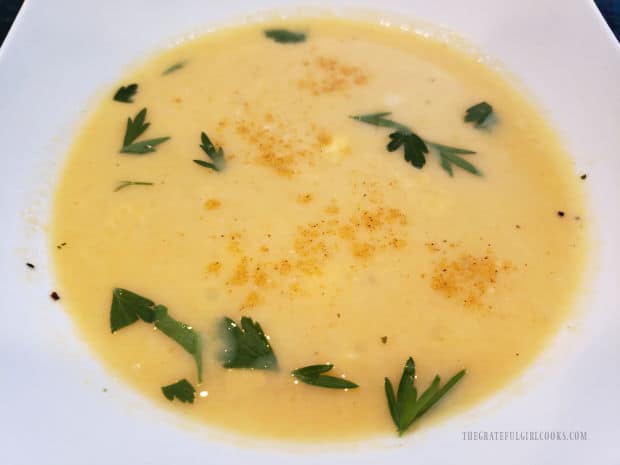 Creamy pumpkin coconut soup, garnished with curry powder and parsley.