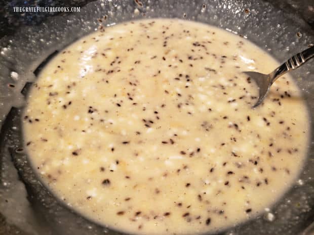 A clear mixing bowl of wet dilly bread ingredients are ready for the flour.