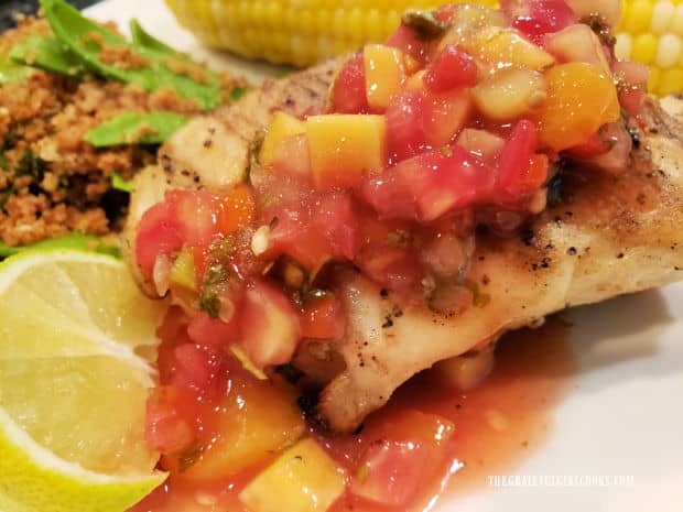 Grilled Garlic Butter Halibut served with mango peach salsa, and a lime wedge.