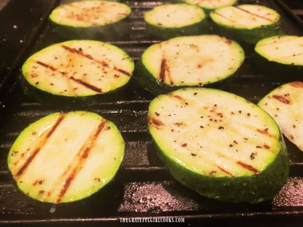 After 2 minutes, the zucchini slices are flipped over, revealing grill marks. 
