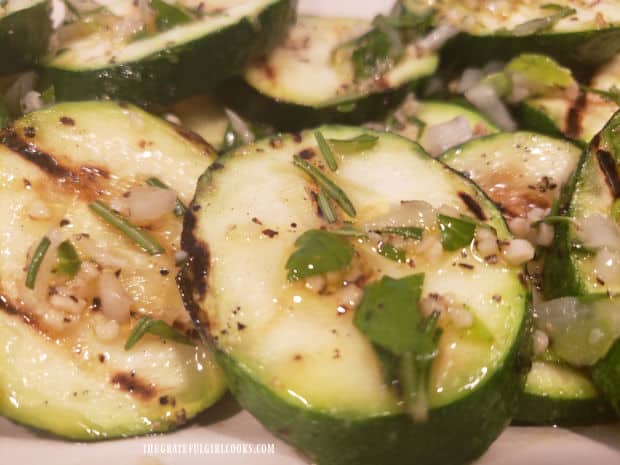 Herb garlic dressing is drizzled over the grilled zucchini slices for serving.