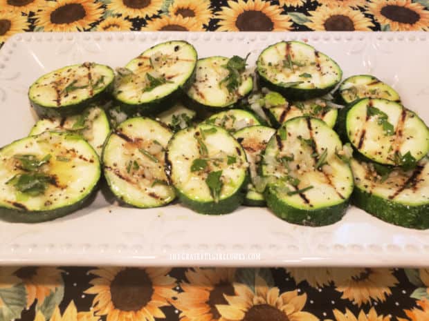 A platter of grilled herb garlic zucchini, ready to be served.