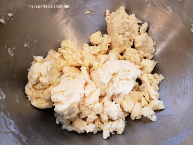 A soft, crumbly dough is formed in the mixing bowl.