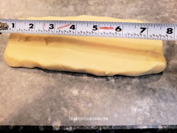 Cookie dough is cut in half, then rectangular logs of dough are rolled.