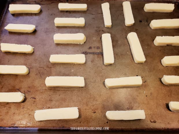 The cookies (which look like large French fries) are put on baking sheet.