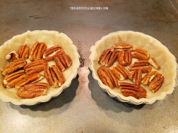Pecan halves are added to the pie dough crust.