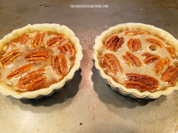 Pie filling is poured over the pecans in the pie crusts.