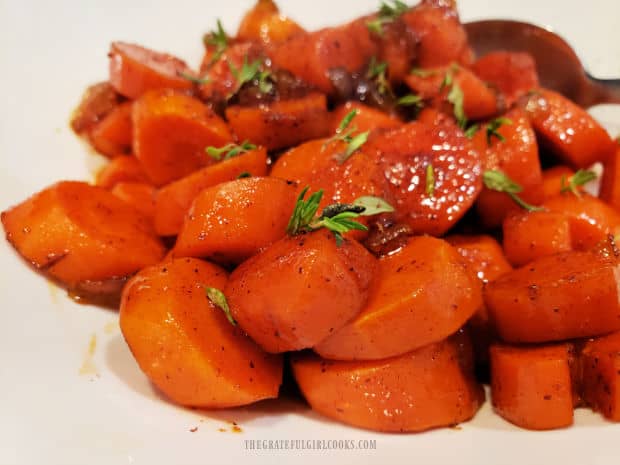 Maple chile glazed carrots are served, garnished with thyme leaves and nutmeg.