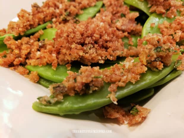 Parmesan crumb sugar snap peas, served on a white platter.