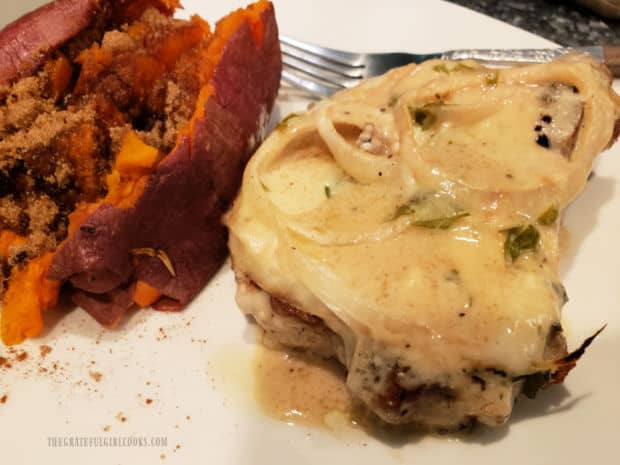 One of the pork chops in sour cream sauce, on plate with a baked sweet potato.