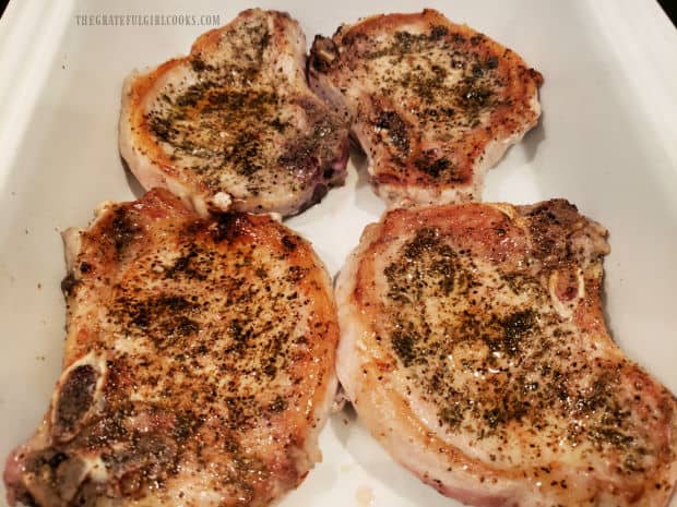 The pan-seared pork chops are placed in a baking dish in single layer.
