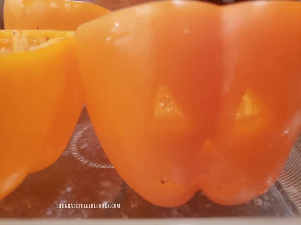 Pumpkin faces are carved out of each orange bell pepper.