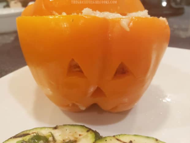 One of the stuffed jack o' lantern peppers, served on a white plate.