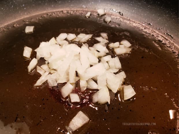 Chopped onions are cooked in olive oil in a skillet.