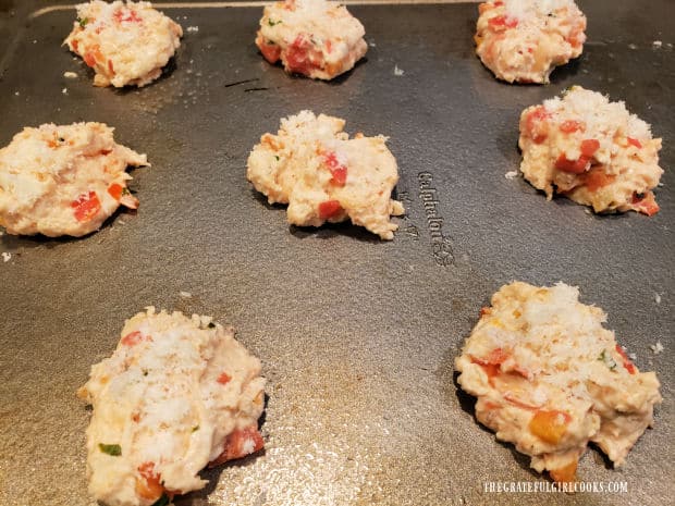 Batter for eight tomato basil drop biscuits is dropped onto baking sheet.