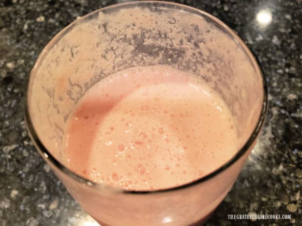 Watermelon pineapple smoothie in a glass is light pink in color.