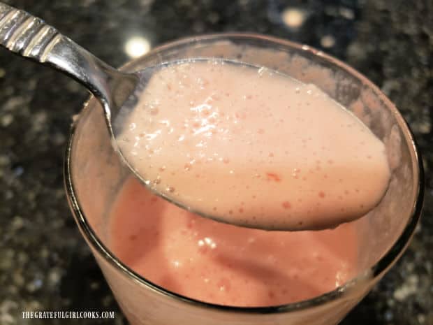 A spoonful of the watermelon pineapple smoothie, held above the cup.