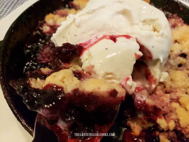 A spoonful of warm blackberry cobbler, with some vanilla ice cream.