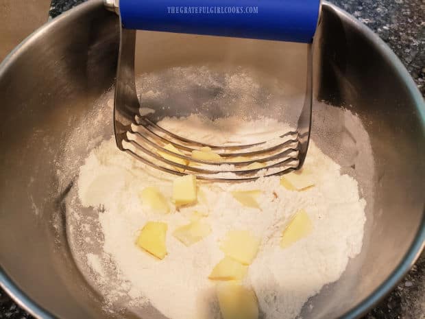 A pastry blender is used to cut cold butter into the cobbler topping ingredients.