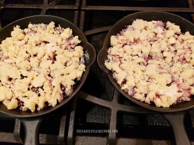 Crumbly dough is placed on top of the blackberry filling in the mini skillets.