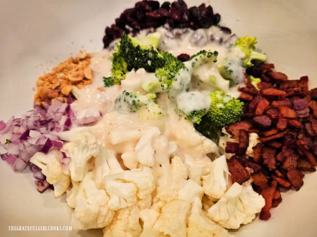 Cauliflower broccoli bacon salad is tossed with creamy salad dressing.