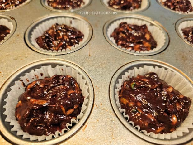 Muffin cups are filled with the chocolate zucchini batter for baking.