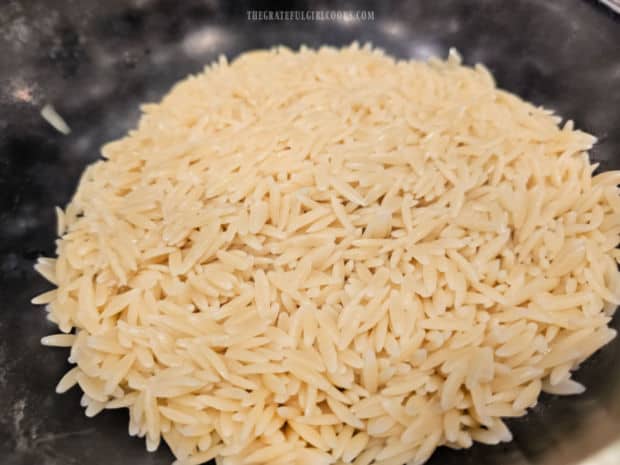 Rinsed and drained cooked orzo is put in a large serving bowl.