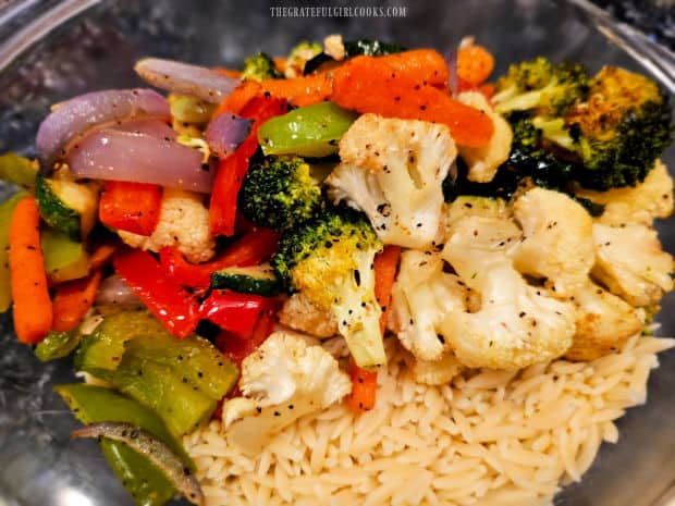 The cooled and roasted veggies are added to the orzo in the bowl.