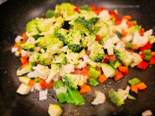 Chopped veggies are cooked in oil in a hot, large skillet.