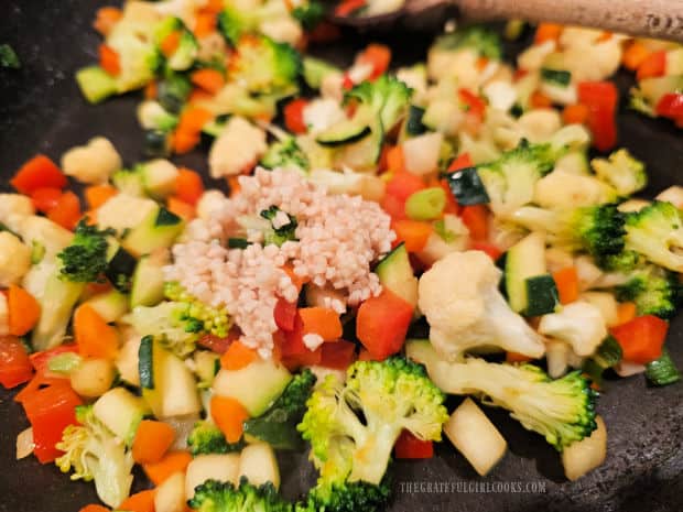 Minced garlic is added to, and cooked with the veggies for the quiche.