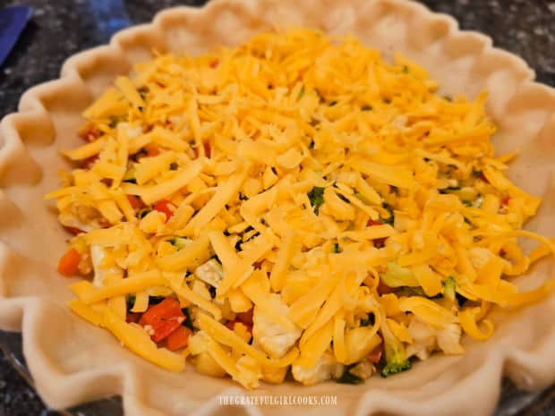 Grated cheddar cheese is added to cover the chopped veggies.