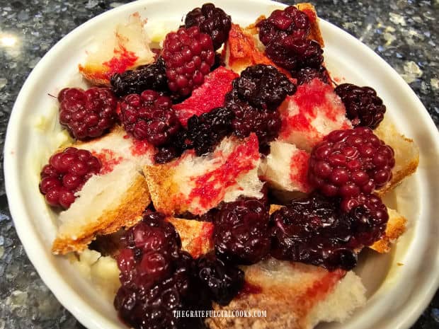 Second layer of bread cubes and blackberries are added to ramekin.