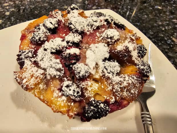 One of the French toast cups (out of the ramekin) served on a white plate.