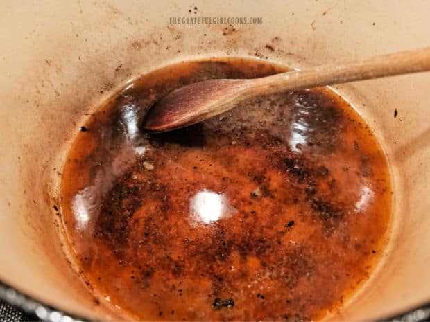 Beef broth and minced garlic are added and used to deglaze the pot.