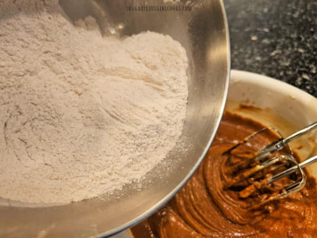 Dry ingredients are slowly added to the gingerbread batter to combine.