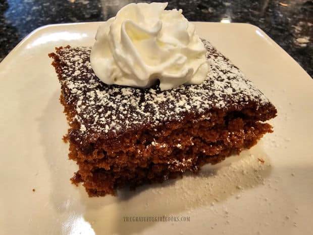 Homemade gingerbread, with powdered sugar and whipped cream on top.