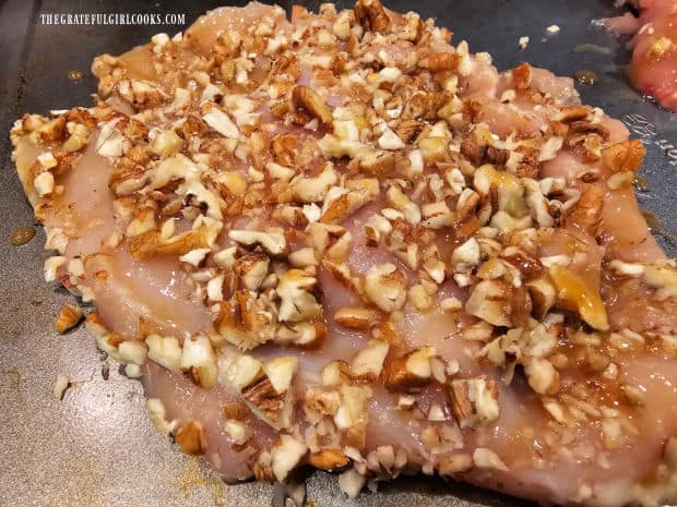 Pecan-crusted chicken, on a baking sheet, ready to be cooked.