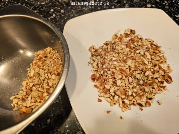 Half cup of chopped pecans to cover the cheese ball, on a white plate .