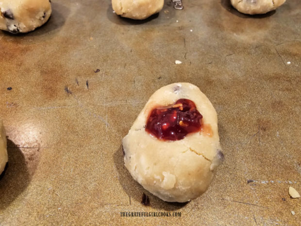 A small amount of raspberry jam is placed in the cookie indentation.