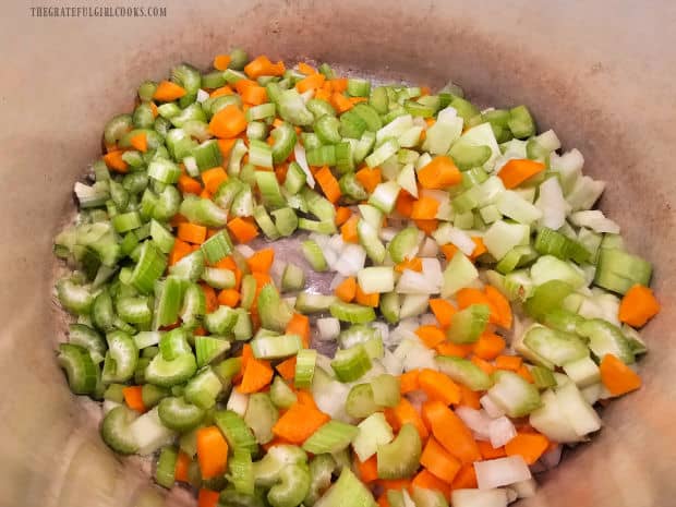 The chopped vegetables are cooked in butter in a large soup pot.