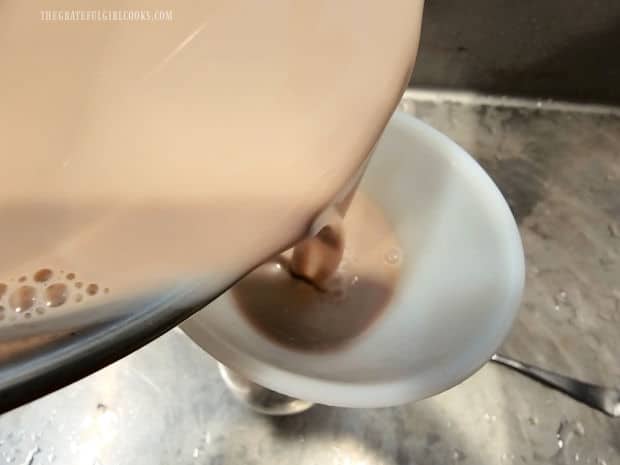 A funnel is used to transfer coconut almond coffee creamer to a bottle.