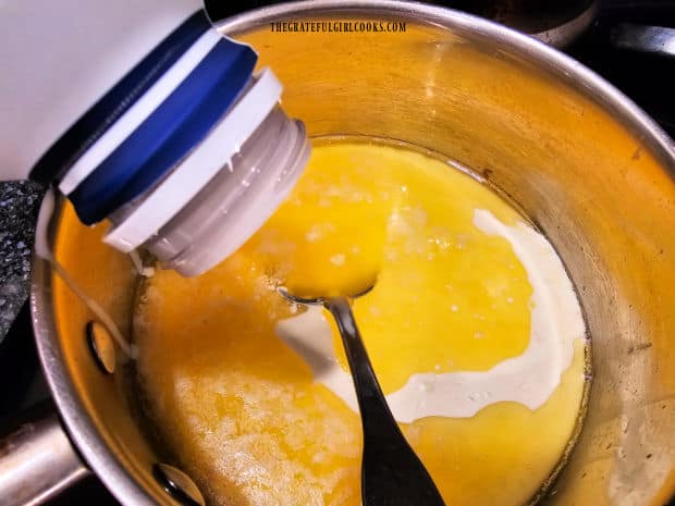 A pint of heavy whipping cream is poured into the melted butter in pan.