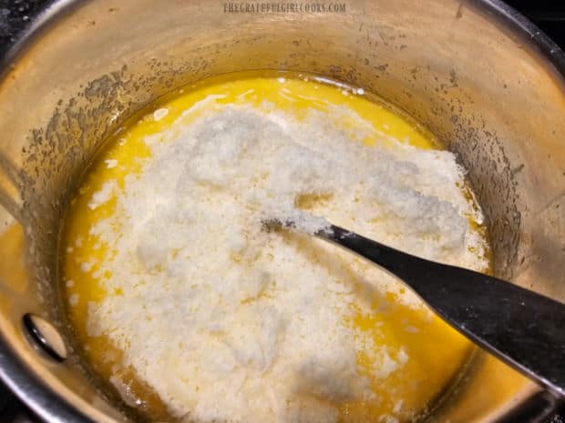 Lots of grated Parmesan cheese is added to the fettucine sauce in pan.