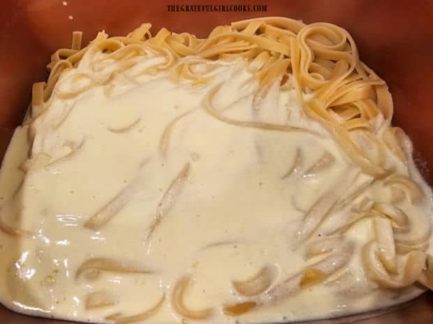 Thick alfredo sauce is poured over the hot pasta and tossed to combine.
