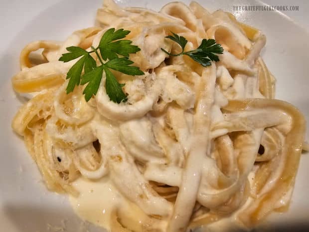 A bowl of Easy Fettucine Alfredo, topped with Parmesan cheese and parsley.