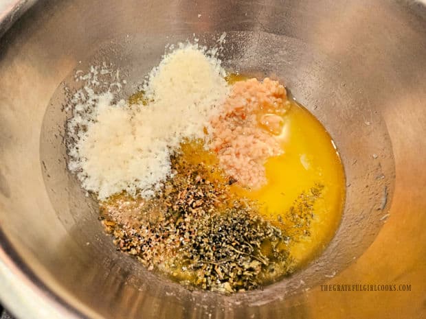 Melted butter, garlic, oregano, parsley and Parmesan are combined in bowl.
