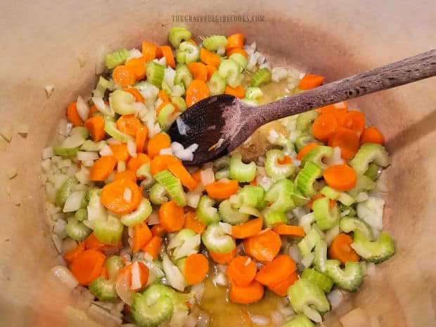 Onion, carrots and celery are cooked in hot olive oil in large soup pot.