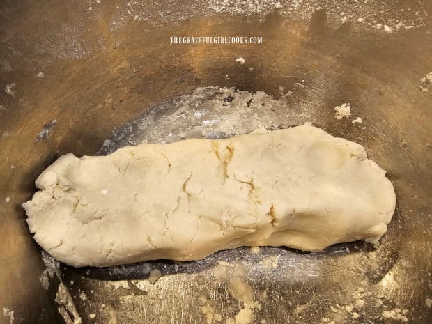 Dough is shaped into a rough rectangular log shape in bowl.